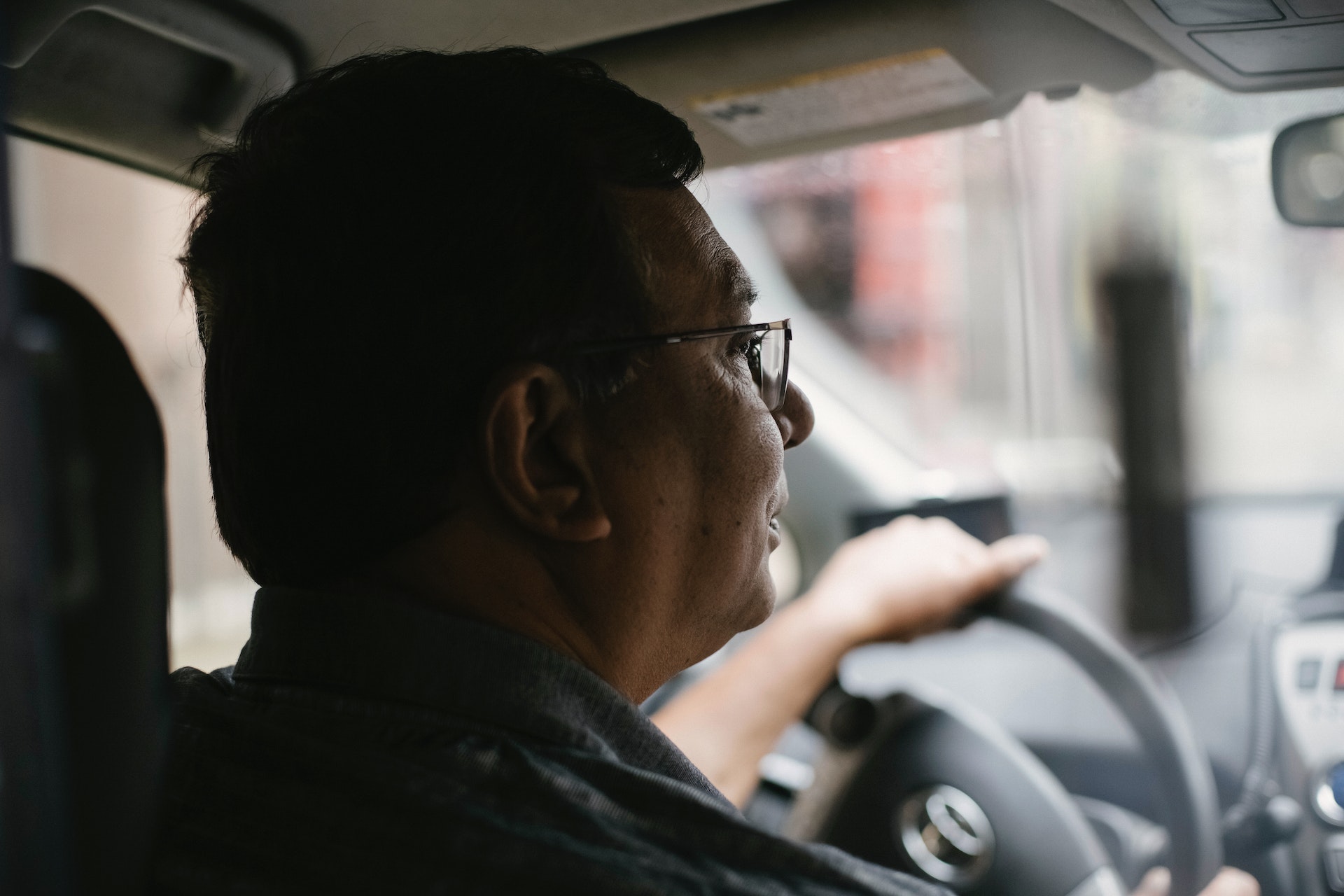 ein älterer herr sitzt am steuer seiner taxis und wartet auf fahrgäste