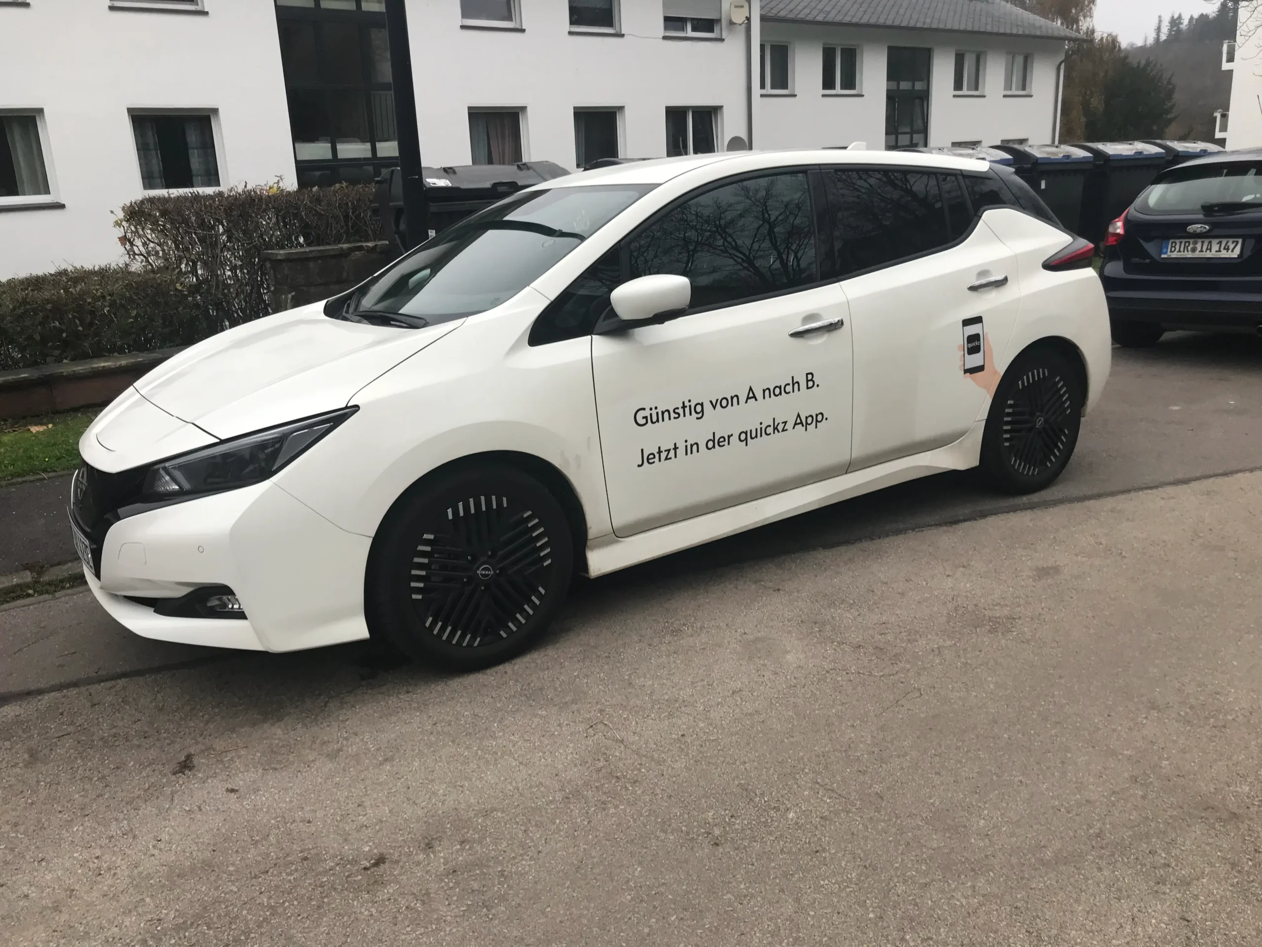 ein weißes auto von quickz mit fahrzeugwerbung. es fungiert als taxi oder mietwagen