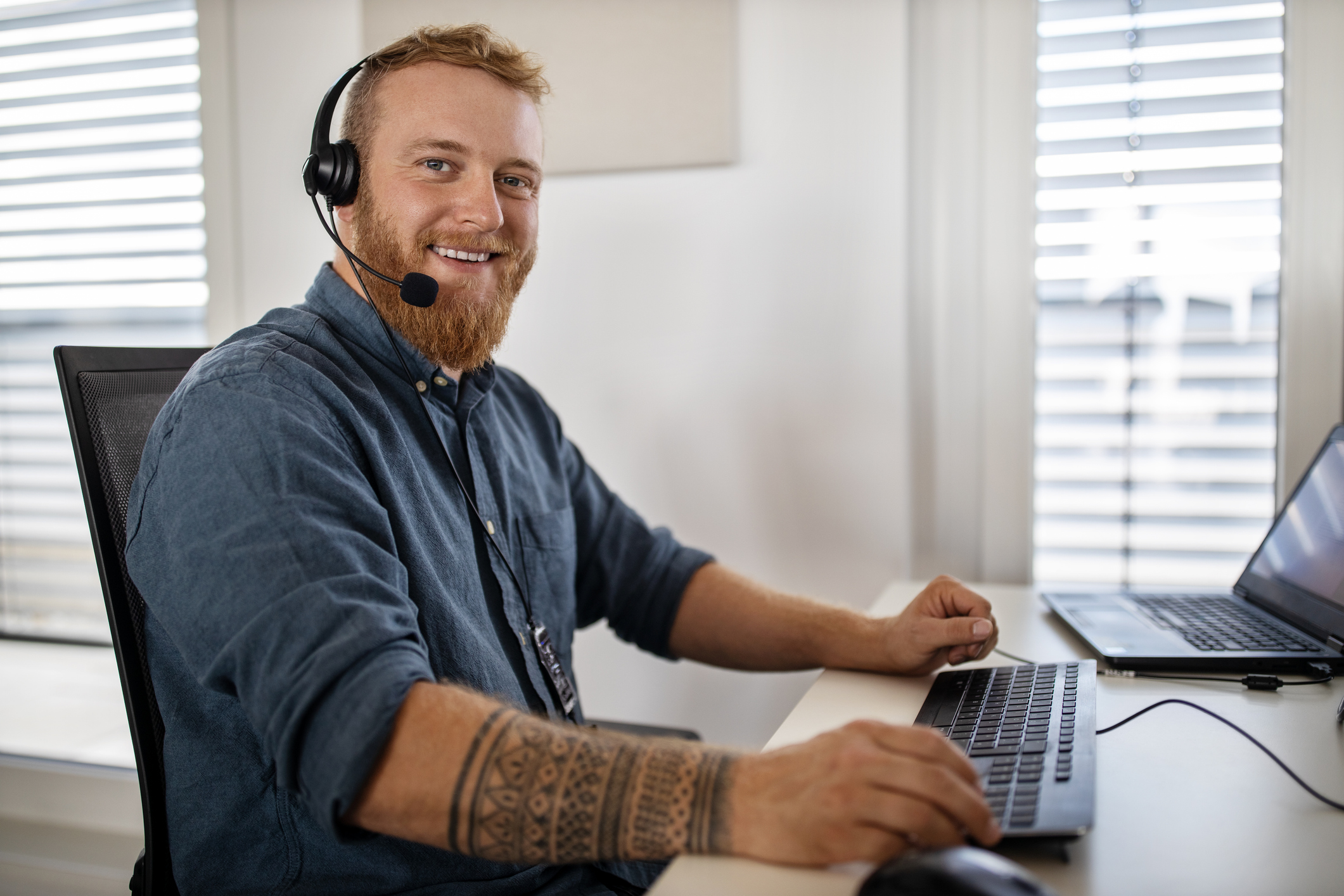 Männlicher Kundenbetreuer am Computer mit Headset beantwortet Kundenanfragen