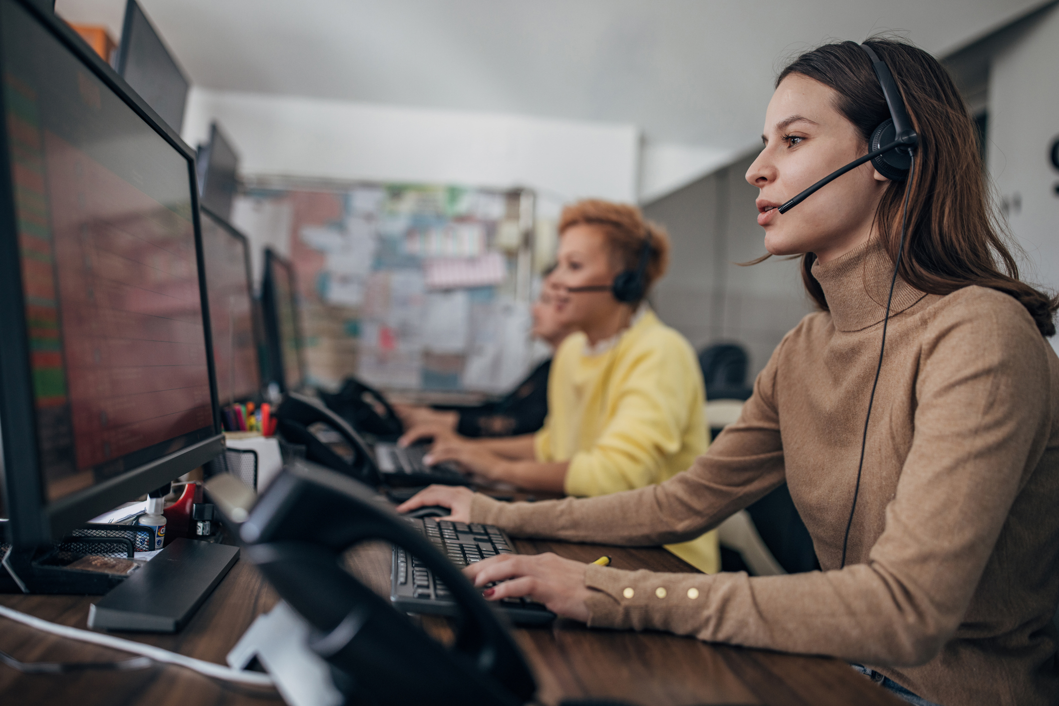 2 Frauen sitzen im Büro und nehmen Anrufe entgegen Call center Disponent Taxizentrale