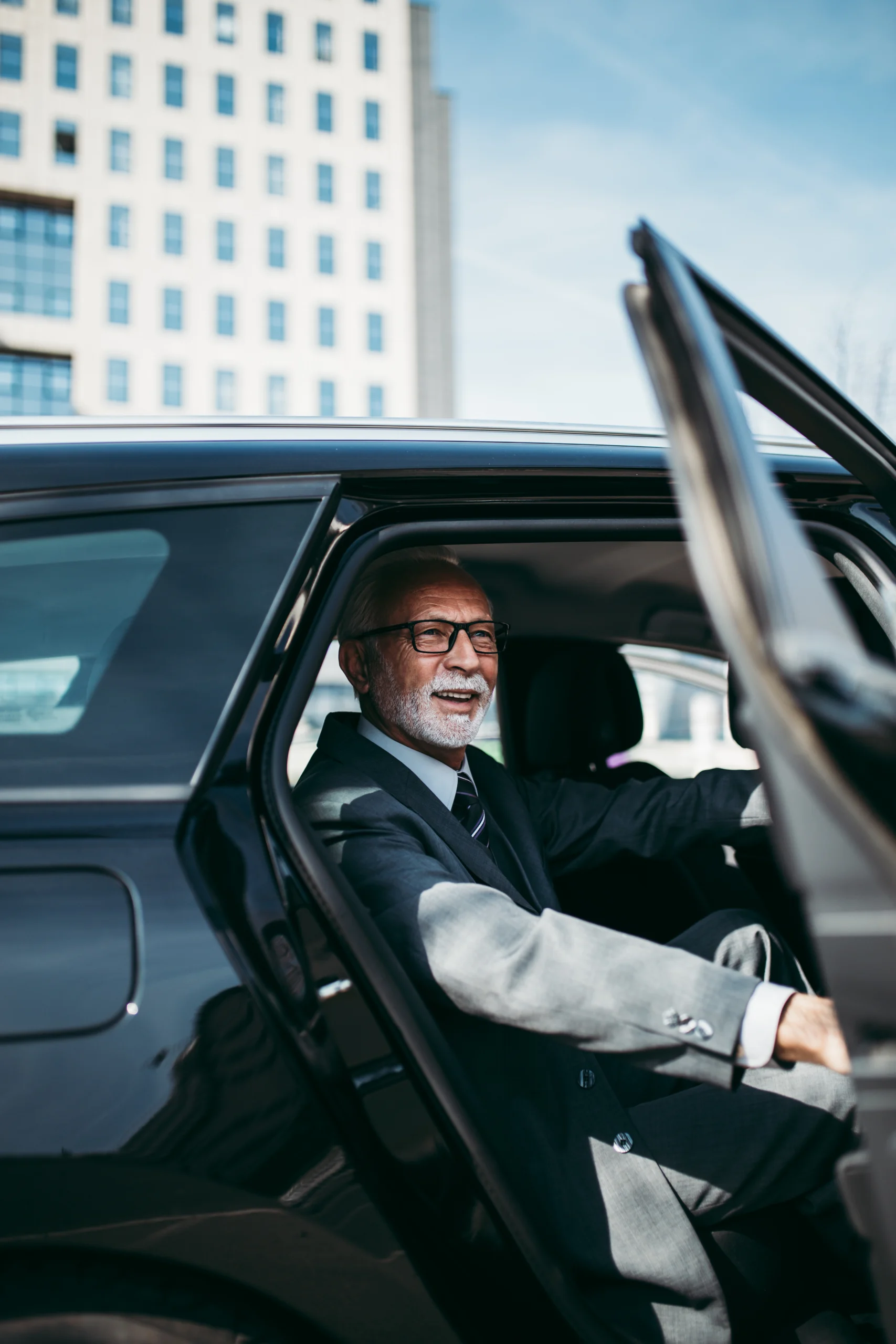 älterer herr im anzug beim aussteigen von der rücksitzbank aus einem auto